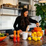 woman standing in front of fruits holding pot's lid